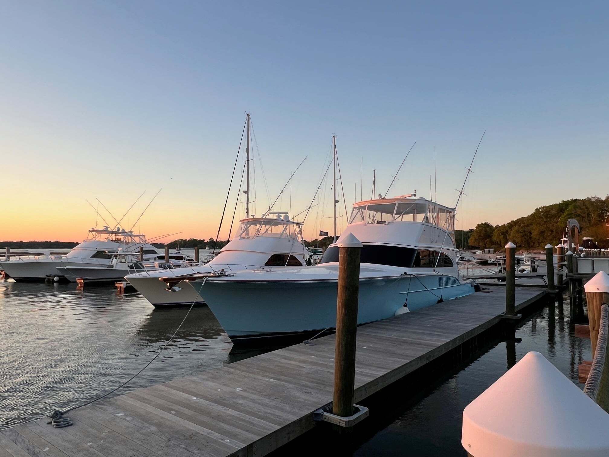 A marina with several yachts docked at wooden piers.