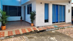 Um edifício branco com grandes janelas, toldo azul e plantas em vasos.