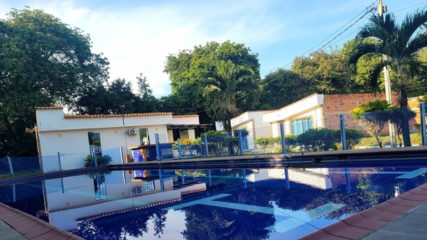 Piscina com água cristalina refletindo os edifícios e árvores ao redor.