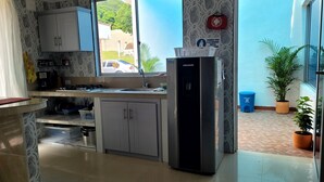 Cozinha compacta com geladeira, pia e armários.