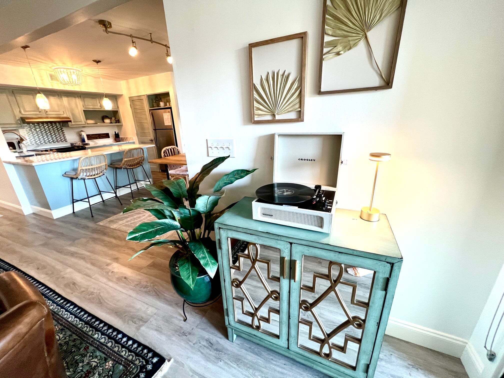 Una cocina moderna con barra, una planta grande en maceta y un tocadiscos antiguo sobre un mueble.