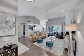 A spacious living area with a modern kitchen, a dining area, and a seating space with a sofa and armchairs. - 1331 Normandy Cir (Palm Harbor)