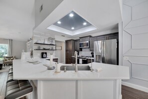 A modern kitchen with a central island, built-in appliances, and a skylight. - 1331 Normandy Cir (Palm Harbor)