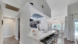 Een moderne keuken met een centraal eiland, barkrukken en uitzicht op de eethoek.