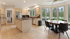 A modern kitchen with a central island, built-in appliances, and a dining area with a large table and chairs. - 12 Siskin (Bend)