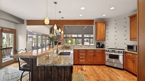 A modern kitchen with a large island, wooden cabinets, and a stone backsplash.