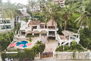 A multi-story resort with a pool, thatched-roof structures, and lush tropical vegetation. - Beachfront Magic @ Casa Campana 7BR (Sayulita)