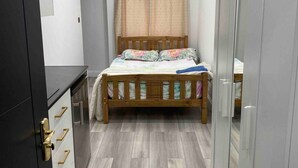 Un dormitorio con una cama de madera, un armario y un espejo.