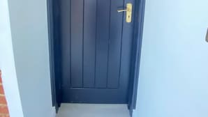 Una puerta oscura con un picaporte sencillo y una cerradura.