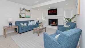 A modern living room with a fireplace, a blue sofa, two armchairs, and a coffee table. - Walk to Beach & Boardwalk • Pool • Family Suite Sleeps 8 • Full Kitchen (Myrtle Beach)