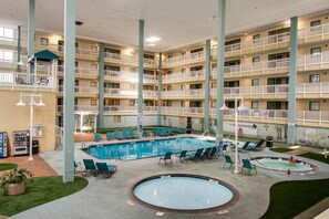 Ein mehrstöckiges Hotel mit einem zentral gelegenen Poolbereich, Sitzmöglichkeiten im Freien und einer Whirlwanne.