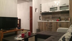 Een moderne woonkamer met een flatscreentelevisie, een bijzettafeltje met tijdschriften en een bank.