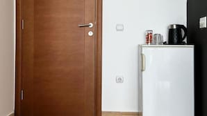 A closed wooden door with a handle, a white refrigerator with a black coffee maker and a glass on top, and a power outlet on the wall. - Casa Mila Apartments - Studio apartment with a sea view (Ulcinj)