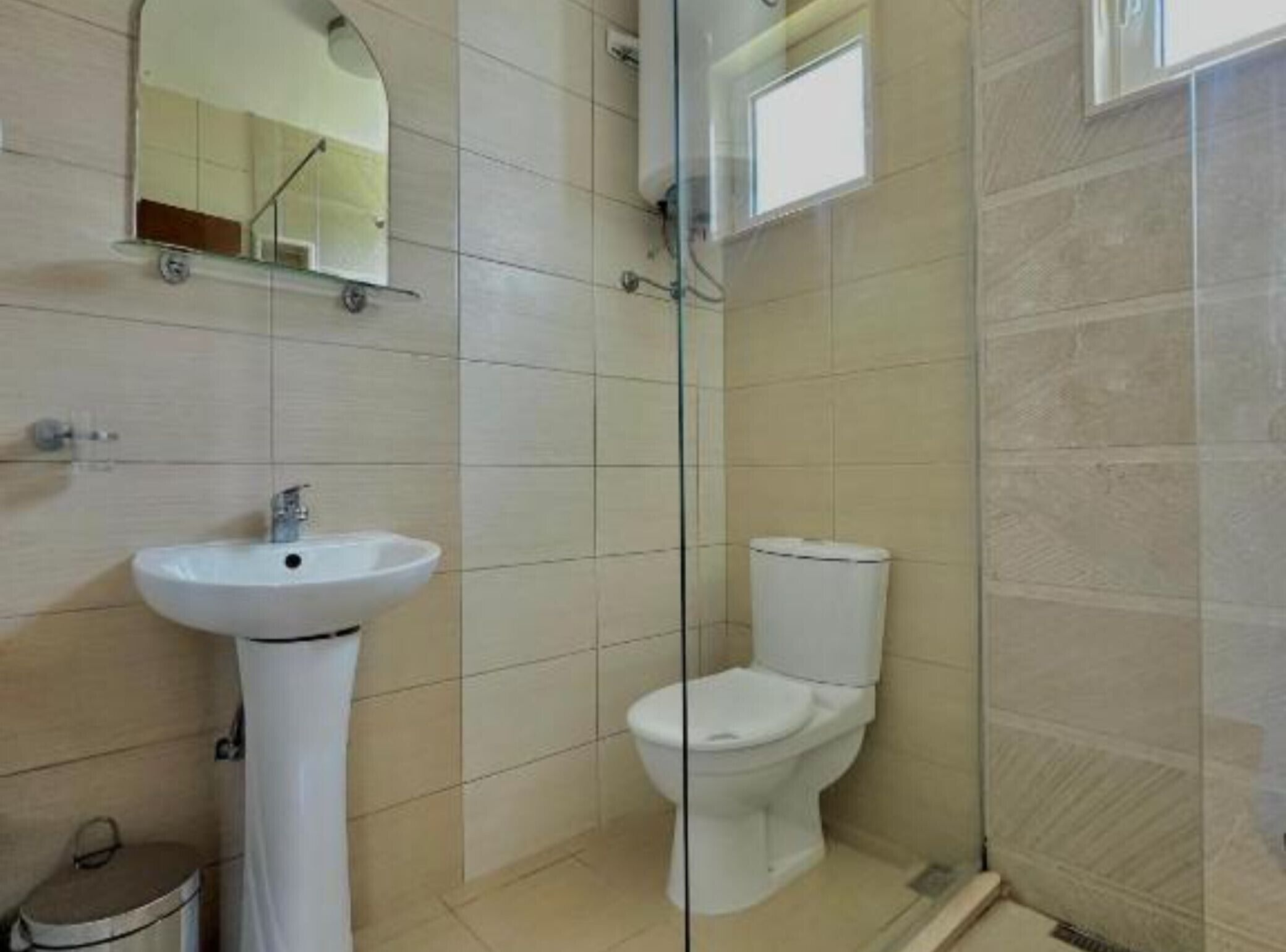 A small bathroom with a sink, toilet, and a mirror.