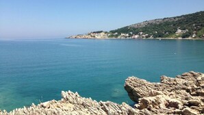 Paesaggio costiero con terreno roccioso e mare cristallino.