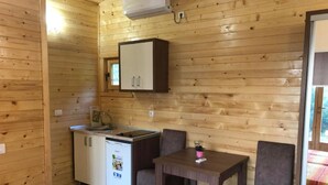 Una habitación compacta con kitchenette, una pequeña mesa de comedor, dos sillas y una cama con un edredón colorido.