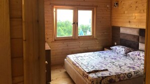 Un dormitorio de cabaña de madera con cama, cómoda y ventana con vistas a la vegetación.