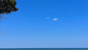 A coastal scene with a clear blue sky, calm sea, and a wooden post extending into the water. - Casa Mila Apartments - Standard Triple bedroom with sea view (Ulcinj)