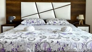 A bedroom with a bed, two bedside tables, and a nightstand. - Casa Mila Apartments - Standard Triple bedroom with sea view (Ulcinj)