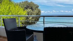 A balcony with a round table and two chairs, overlooking a body of water and greenery. - Casa Mila Apartments - Standard Triple bedroom with sea view (Ulcinj)