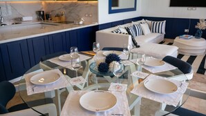 Un espace repas moderne avec une table en verre dressée pour six personnes, des assiettes blanches et des verres à vin.