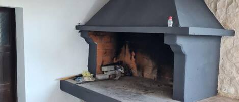 Un camino in pietra con una mensola nera, una piccola bottiglia in cima e un fuoco acceso all'interno.