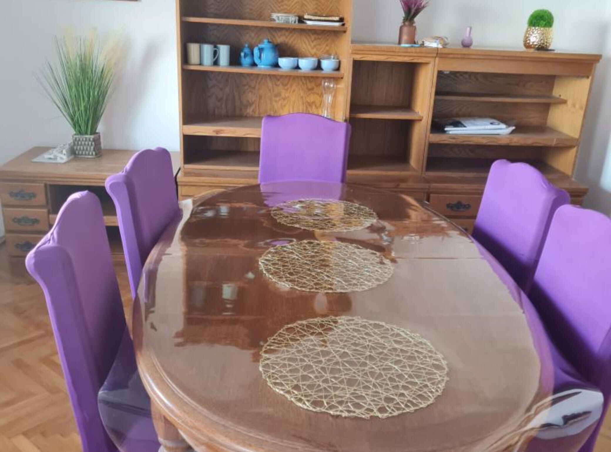 A dining table with purple chairs and three woven placemats.