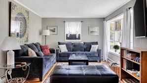 A living room with two sofas, a coffee table, a lamp, and a TV. - Saratoga Track House, Pet Friendly, Workspace (Saratoga Springs)