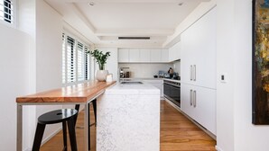 Una cocina moderna con armarios blancos, encimera de madera e isla de mármol.