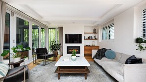 Una sala moderna con chimenea, un sofá, una mesita de centro y un televisor montado en la pared.