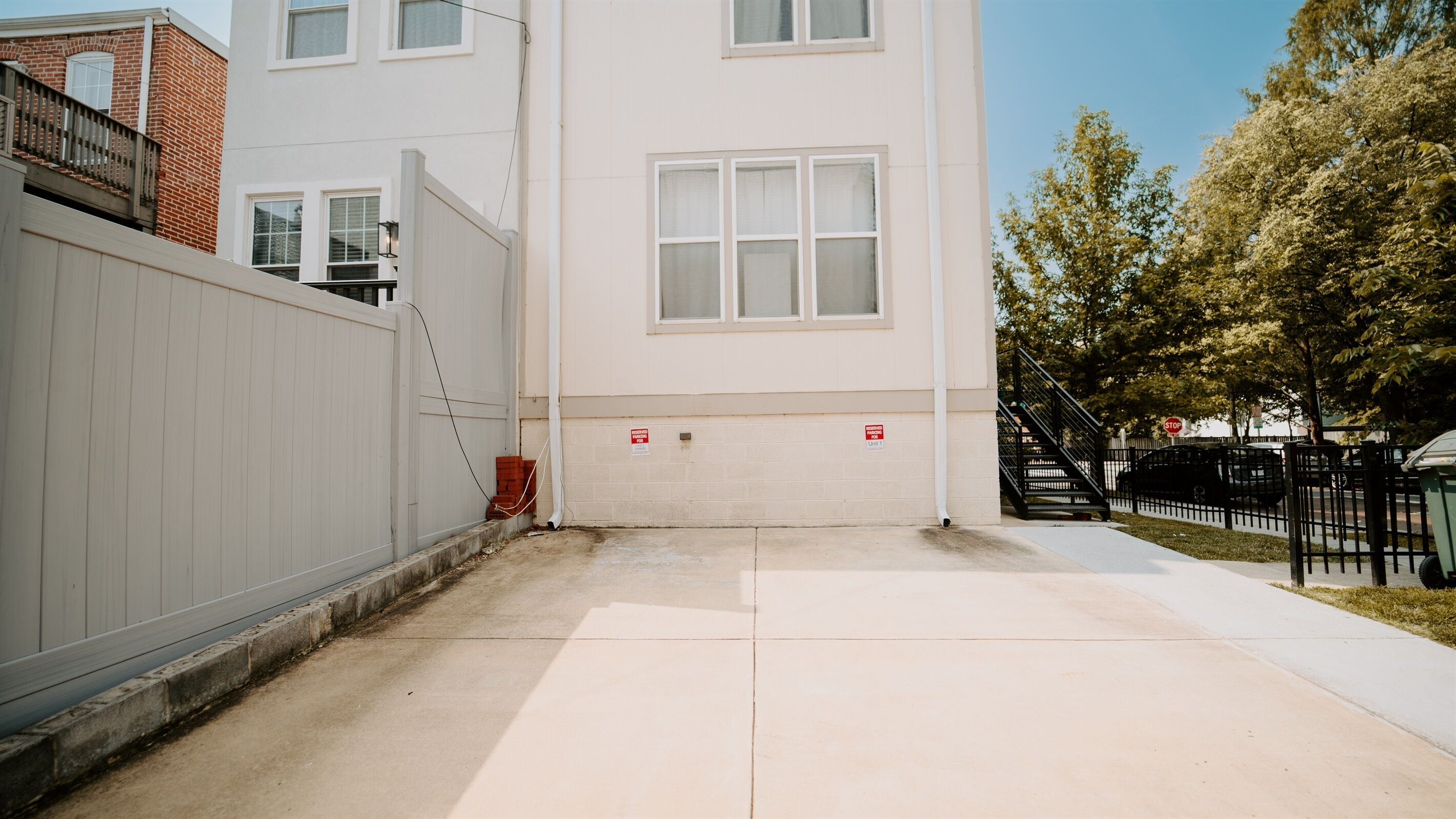 A building with a white exterior, a gated entrance, and a visible fire alarm panel.
