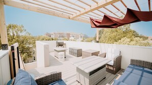 Una terrazza sul tetto con mobili da esterno, una pergola e vista su edifici sullo sfondo.