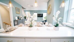 Una cucina moderna con una grande isola, mobili bianchi e illuminazione a sospensione.