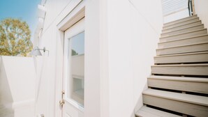 Un edificio con facciata bianca e una scala in legno che conduce a una porta finestrata.