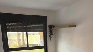Una camera da letto moderna con un letto, una finestra con persiane, un comodino e una pianta pensile.