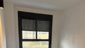 Una piccola camera con un letto singolo, una finestra, un termosifone e un asciugamano verde sul letto.
