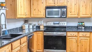 A kitchen with wooden cabinets, a microwave, stove, and oven. - Gate City Grotto (New Owners) (Pocatello)