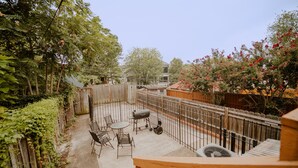 Un jardin avec une clôture en bois, un barbecue et une table avec des chaises.