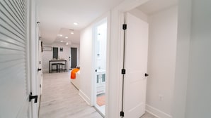 A hallway with white walls and a wooden floor leading to a dining area with a table and chairs. - Comfy 1BR Basement DC | Sleeps 5 | Near Metro (Washington DC)