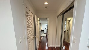 A hallway with wooden flooring, white walls, and doors leading to other rooms. - Historic English Basement – Elegant Old Town, Alexandria Retreat (Alexandria)