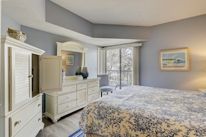 Une chambre avec un grand lit, une commode, une chaise, une fenêtre donnant sur un beau paysage et un tableau accroché au mur.