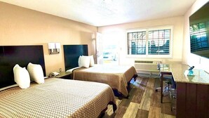 A hotel room with two beds, a desk, and a large window with blinds. - Kermit Inn (Kermit)
