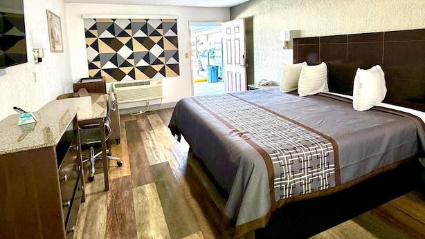 A hotel room with a large bed, a desk with chairs, and a patterned wall. - Kermit Inn (Kermit)