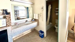 A bathroom with a sink, mirror, hairdryer, and shower. - Kermit Inn (Kermit)