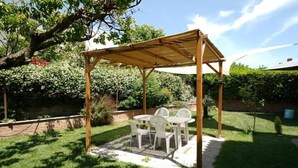 Eine hölzerne Pergola mit Tisch und Stühlen in einem Garten.