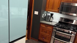 A kitchen with wooden cabinets, a stainless steel oven, and a microwave. - Charming Furnished Tudor Revival in the Heart of Historic California Heights (Long Beach)