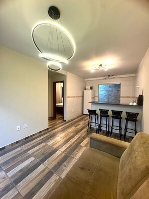 Cozinha moderna com área de bar, espaço de jantar com sofá e piso estampado.