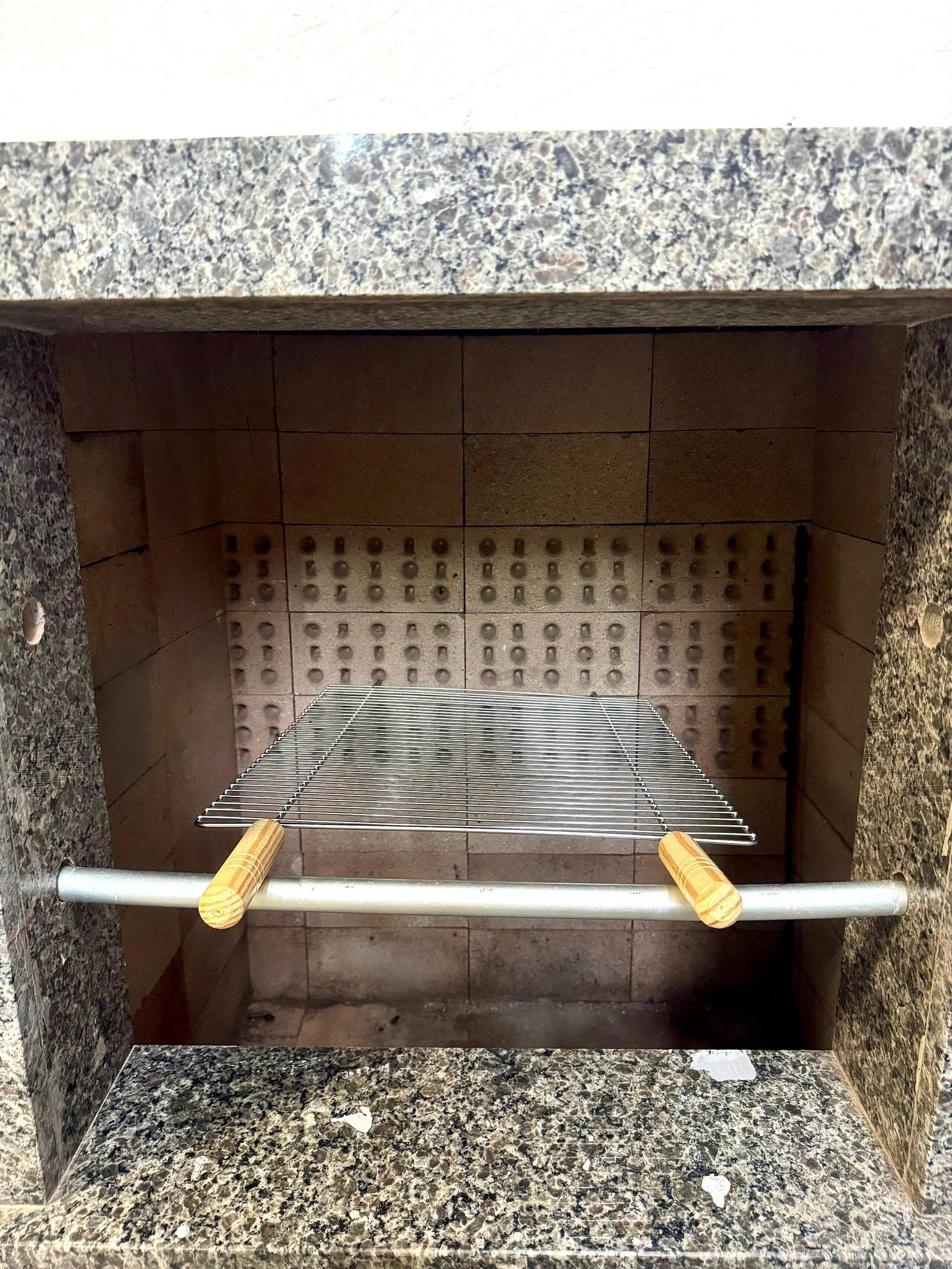 A metal rack with wooden handles inside a stone-walled structure.