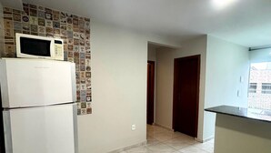 Eine Küche mit Kühlschrank, Mikrowelle und Fliesenboden.