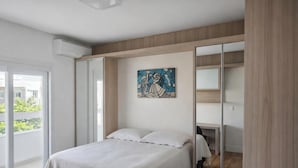 Une chambre à coucher avec un lit, un bureau, une grande fenêtre et un tableau au mur.